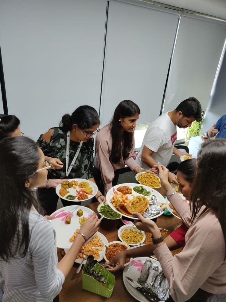Colleagues sharing plates of biryani and snacks at an office gathering